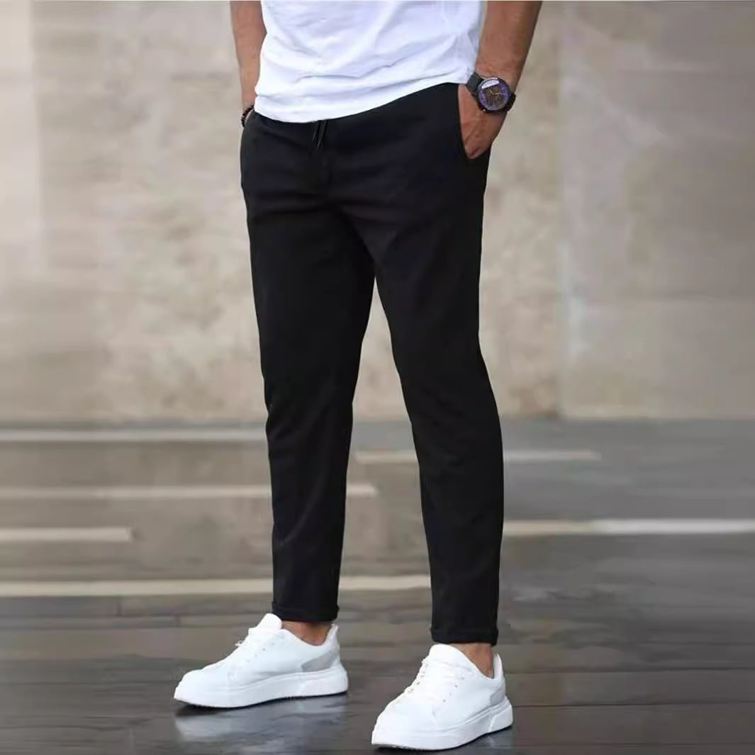 Mens casual pants in Black, tapered leg with drawstring waist, worn with white sneakers