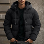 Mens puffer jacket in Black with drawstring hood, worn over a black tee