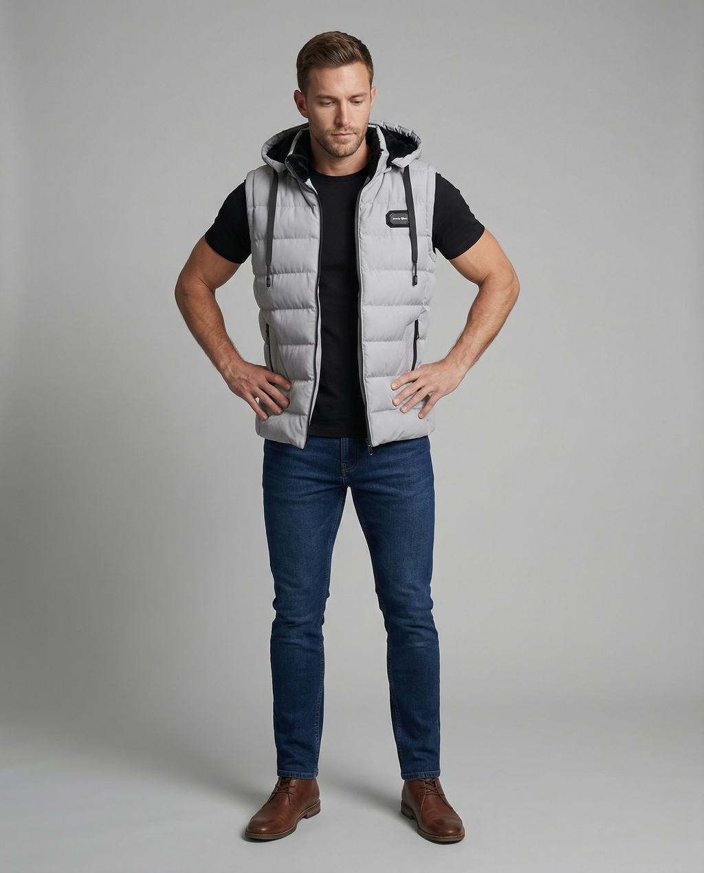 Mens puffer vest with hood in Gray, full-length front view with jeans