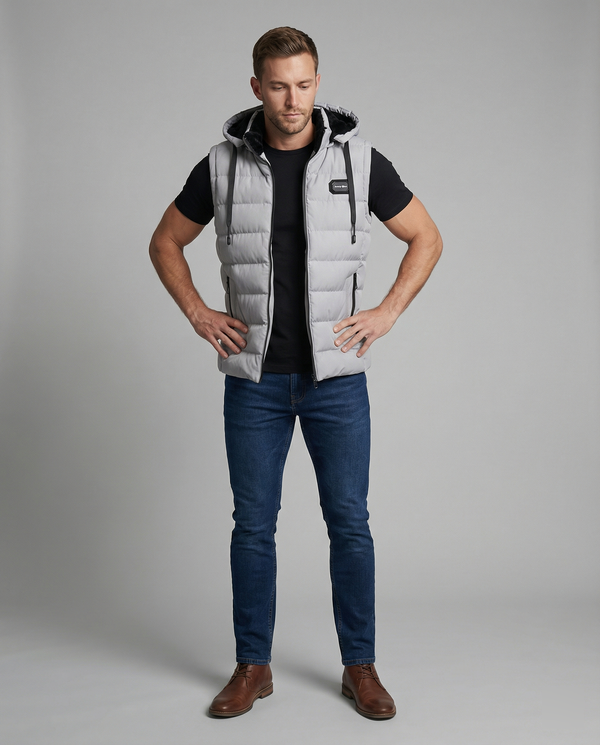 Mens puffer vest with hood in Gray, full-length front view with jeans