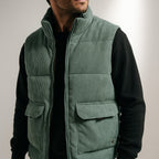 Mens corduroy puffer vest in Green, worn over a black sweater